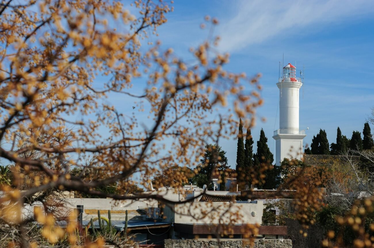 a white light house with trees in the foreground